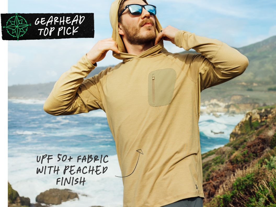 A man looks cool wearing reflective sunglasses and a hoody near the ocean. Text overlay reads: gearhead top pick upf 50+ fabric with peached finish.